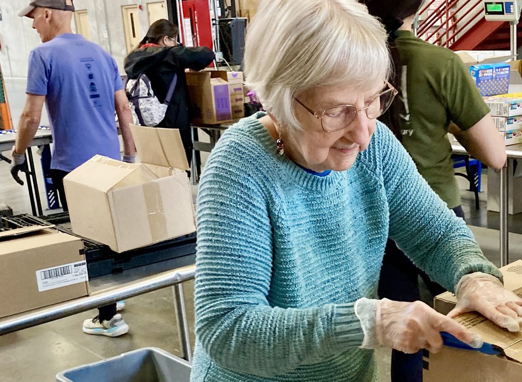 Pat helps out during a service event at the Food Bank of Northern Nevada by opening boxes and sorting food products.